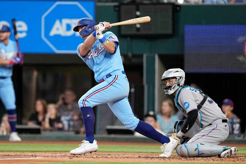 Texas Rangers' Josh Jung, front left, follows through on a swing as Miami Marlins catcher...