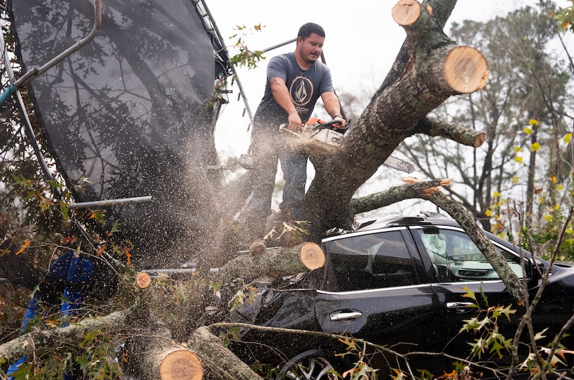 Saul Rodriguez uses a chain saw to remove debris in the Greater Houston region Dec. 28,...