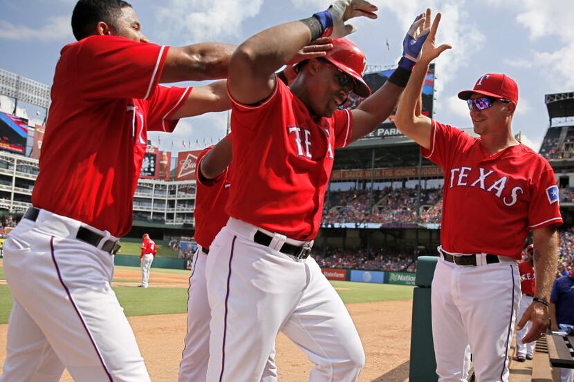 Teammates congratulate Texas Rangers third baseman Adrian Beltre as he scored a home run...