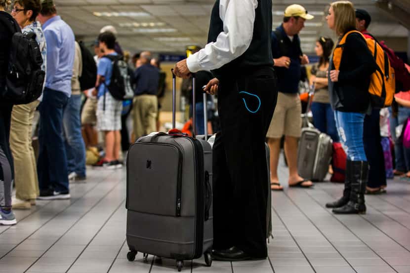 A traveler stands with his bags as luggage moves around a baggage claim at Gate C on Friday,...