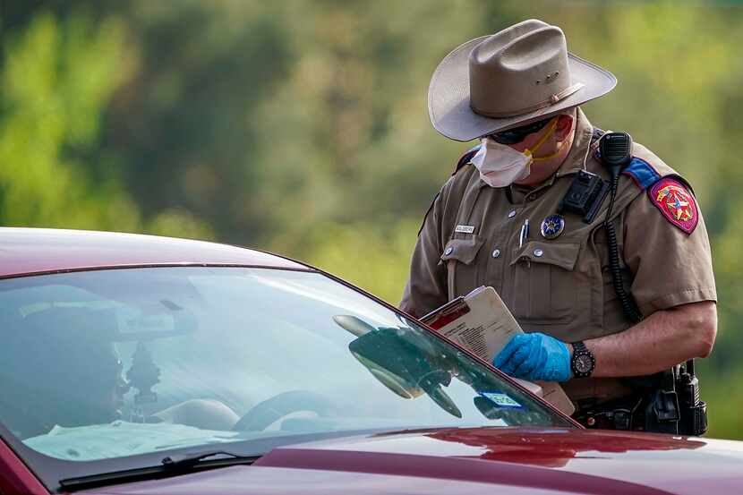 A Texas Department of Public Safety State Trooper talks with a motorist at a checkpoint on...