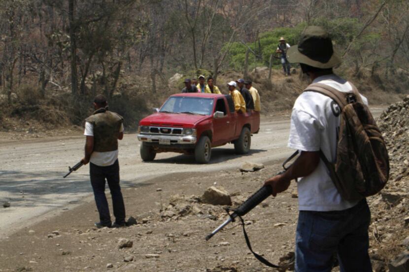 In this May 20, 2013 photo, armed men belonging to a local self-defense group stand guard as...