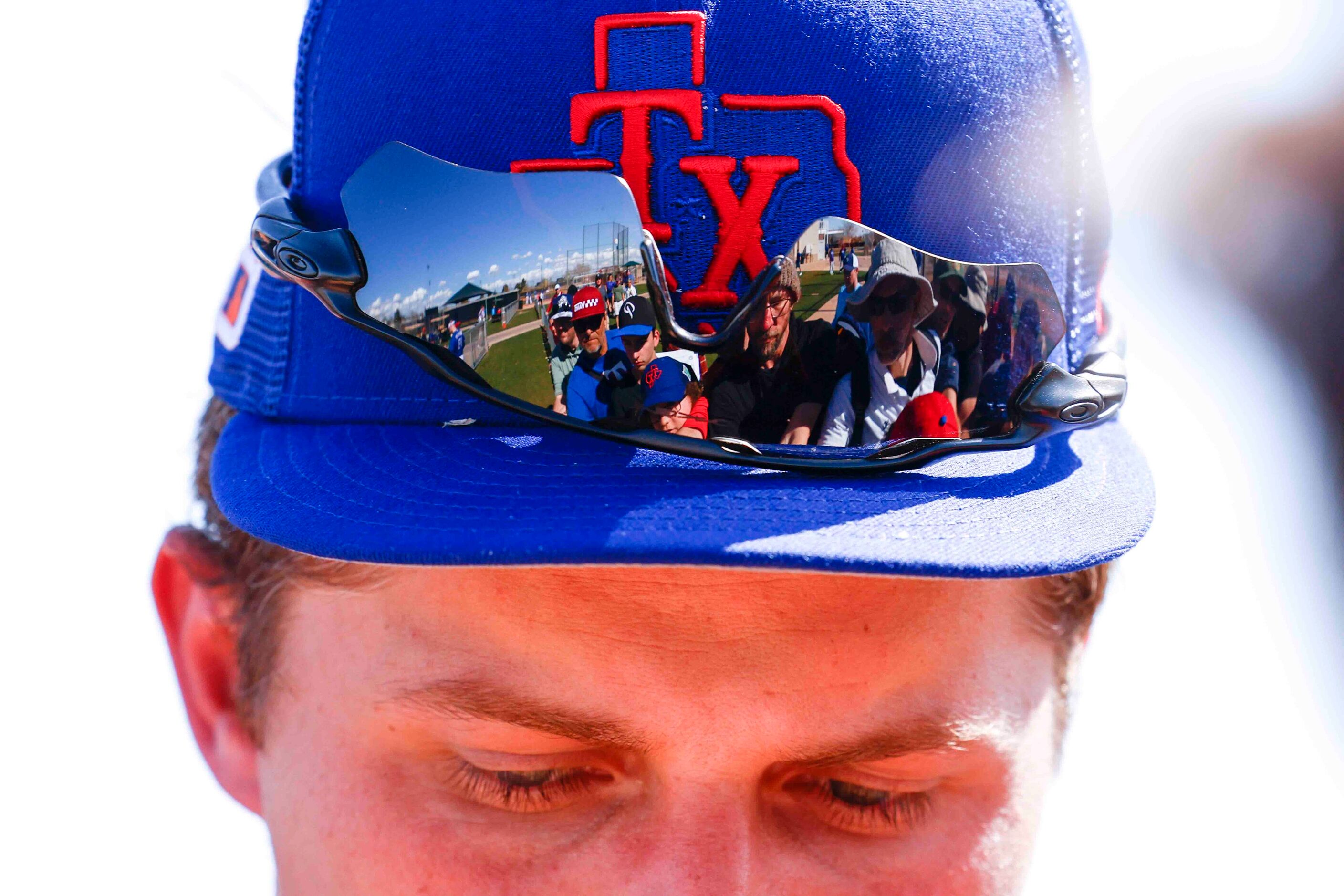 A crowd seeking autographs is reflected on the sunglass of Texas Rangers shortstop Corey...