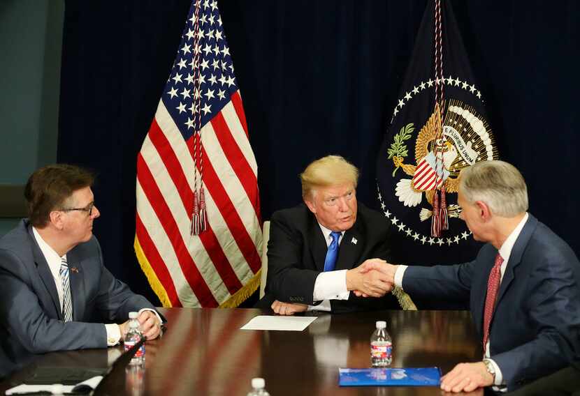 President Donald Trump shakes hands with Texas Gov. Greg Abbott as they and Lt. Gov. Dan...