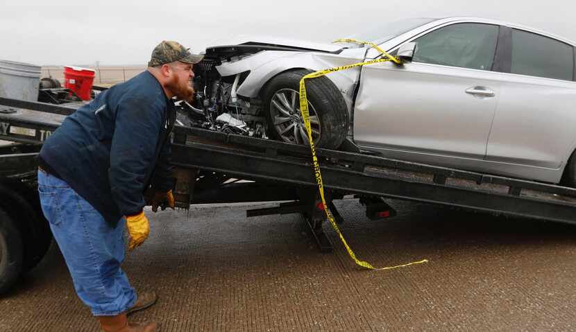 David Messer, of J & S Towing, hooks up a wrecked car on a ice covered Highway 67 at the...