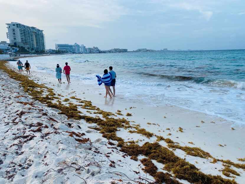 Tourists walk the beaches of Cancún on July 12, as the resurgence of the coronavirus brings...