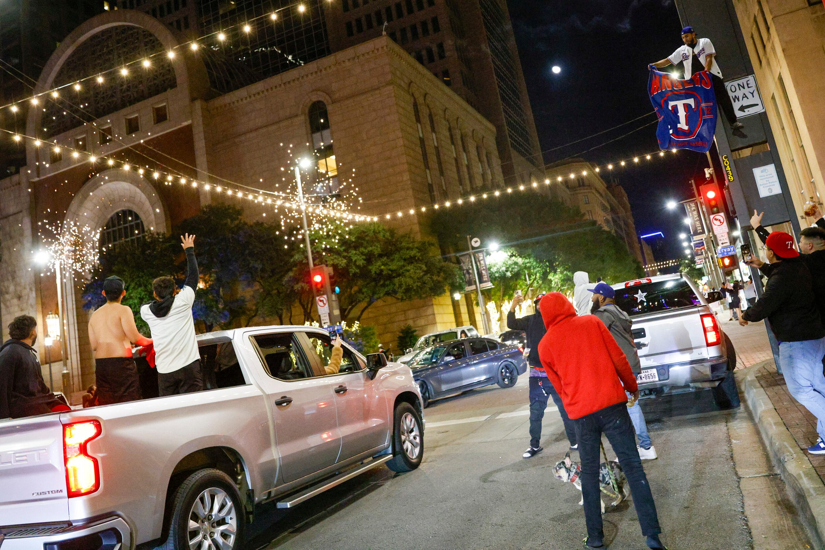 A man sits atop a stop light at Main and Ervay Streets as fireworks explode over the...