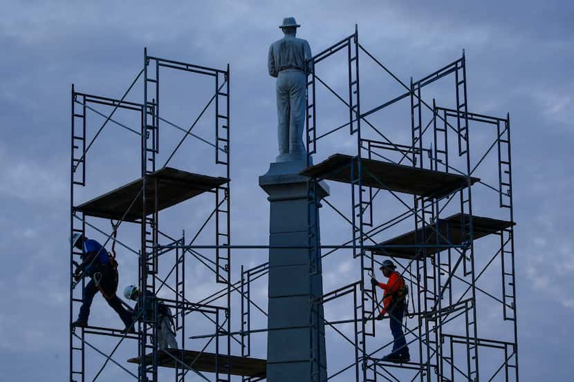 Construction crews work to remove The Confederate War Memorial at Pioneer Park on Wednesday,...