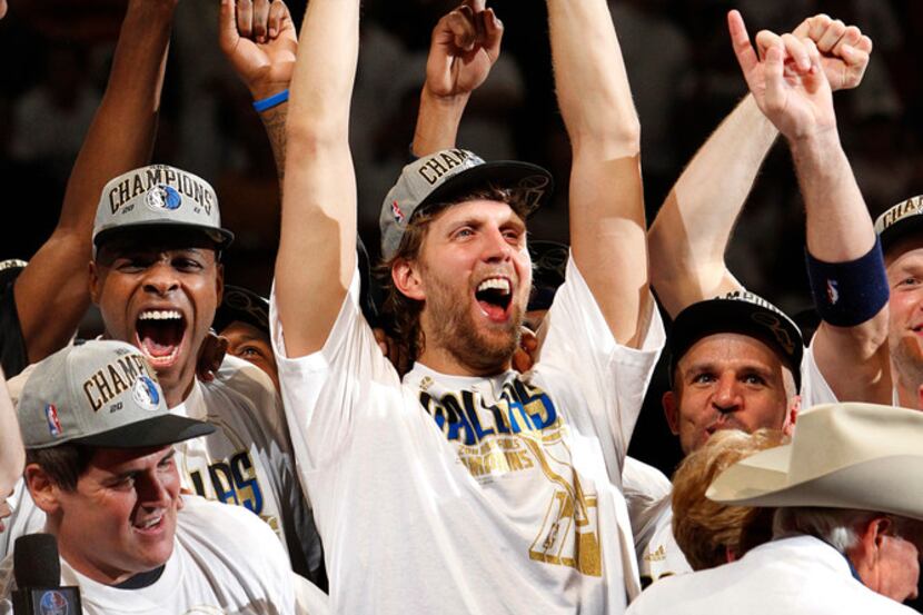 Dallas Maverick Dirk Nowitzki raises the Larry O'Brien NBA Championship Trophy alongside his...