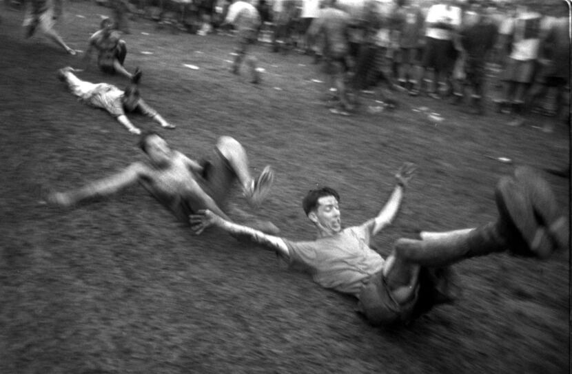Lollapalooza 94 concert goers slide  down a muddy embankment at the Starplex during a...