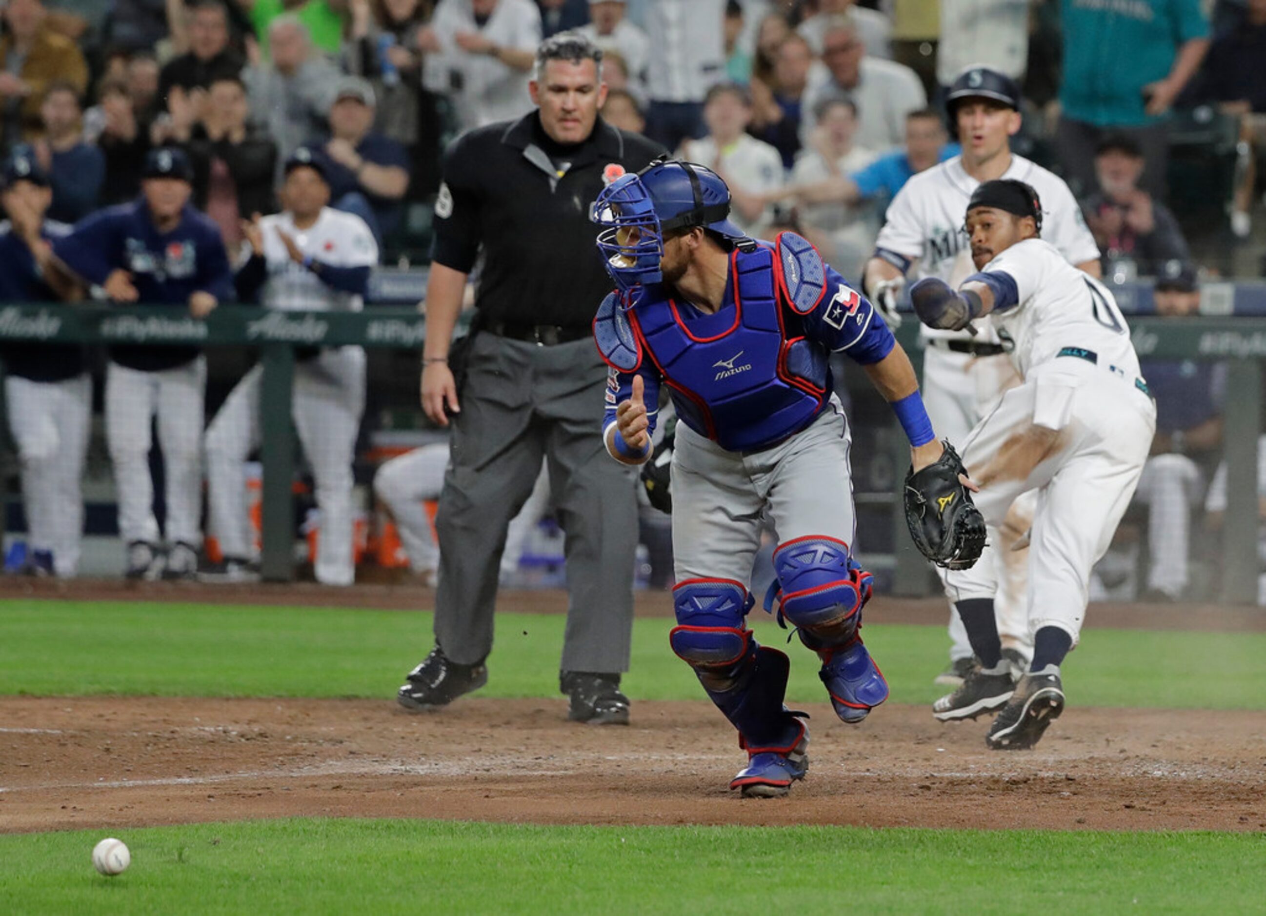 Seattle Mariners' Mallex Smith, right, safely steals home to score a run as Texas Rangers...