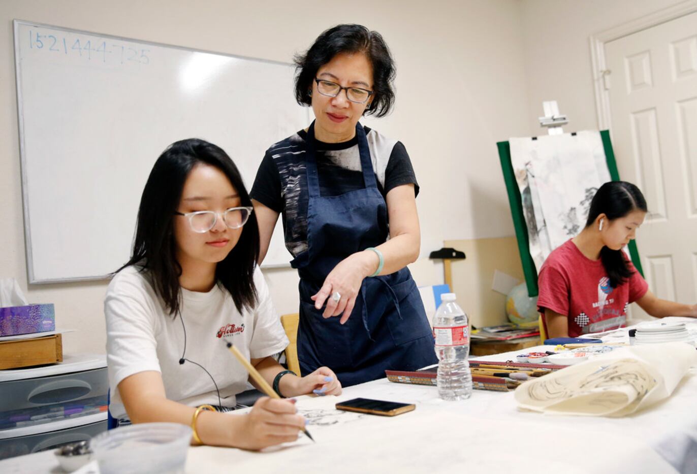 Local artist Jenney Chang (center) works with Katherine Wang, 19, of Plano, on Wang's Gong...