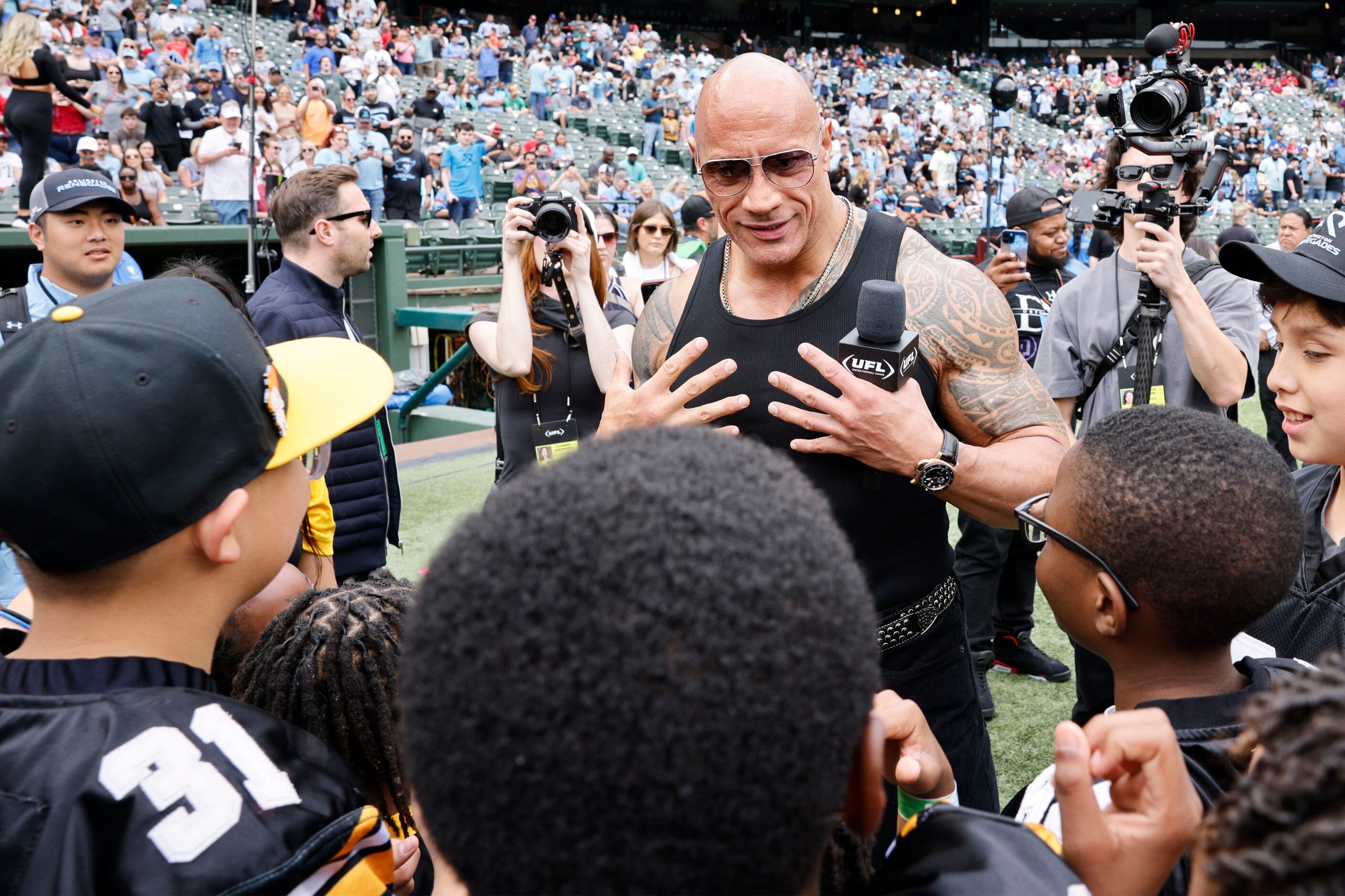 Dwayne "The Rock" Johnson speaks to children before a football game between the Arlington...