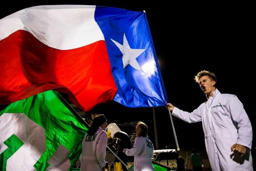 Carroll Crew member Billy Wade cheers as he holds up a Texas flag before their game against...