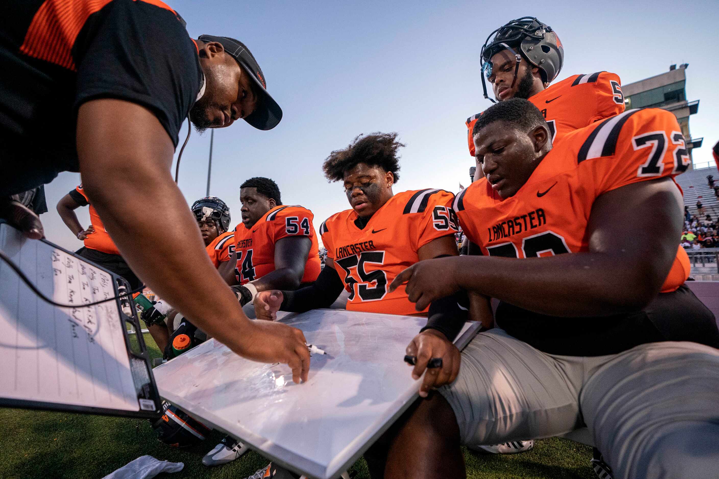 Lancaster offensive line coach Jarrett Golightly reviews plays with senior offensive linemen...