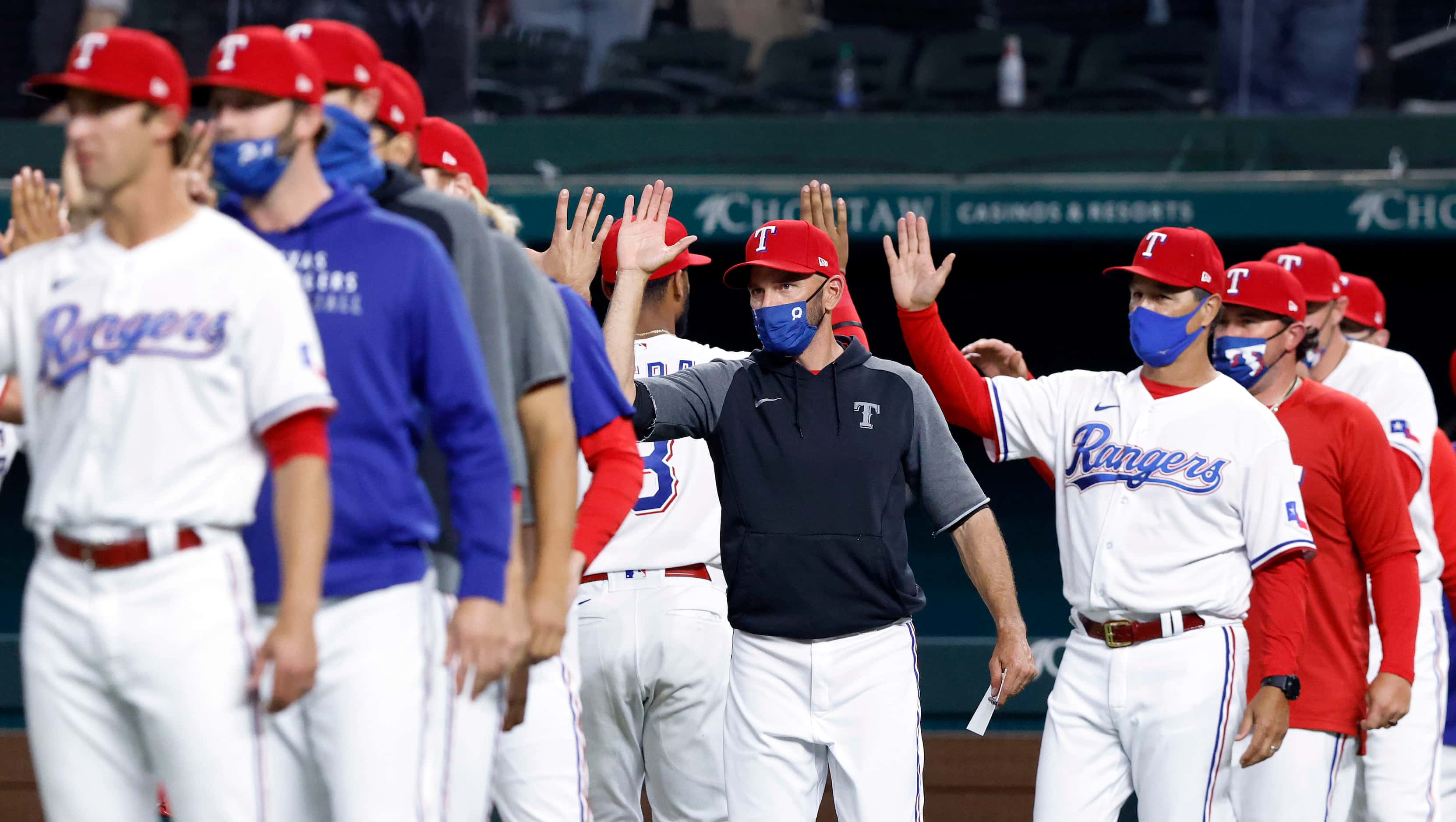 Texas Rangers manager Chris Woodward (center) congratulates his players after they defeated...