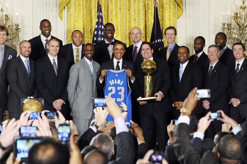US President Barack Obama (C) holds a jersey as he poses with the NBA Champion Dallas...
