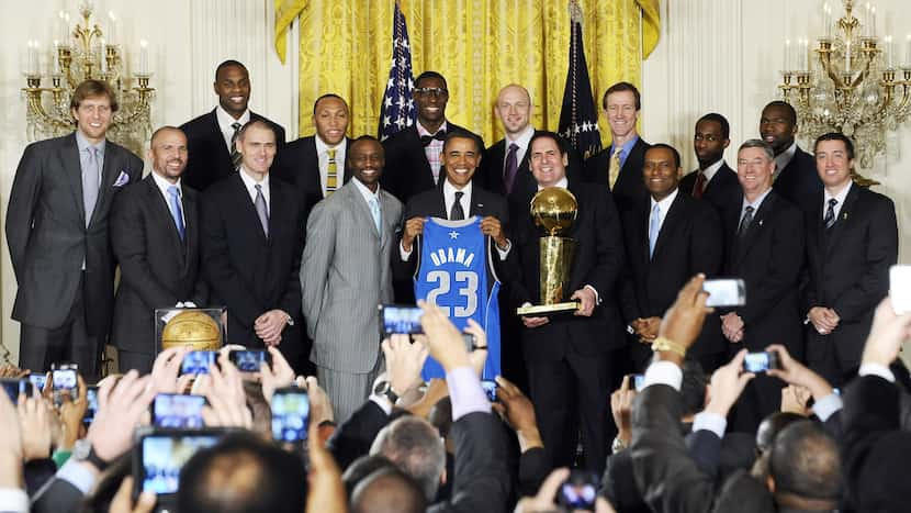 US President Barack Obama (C) holds a jersey as he poses with the NBA Champion Dallas...