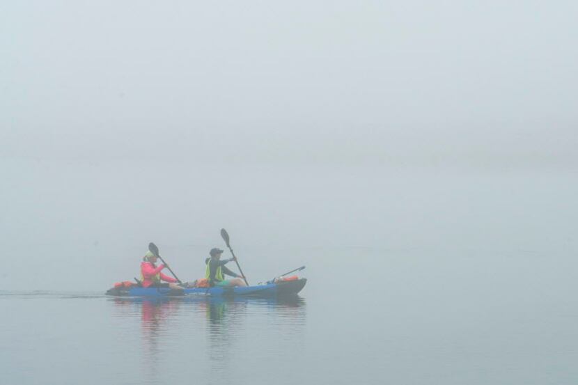 Volunteers with the Bolsa Chica Conservancy paddle their kayak through the fog at the Bolsa...