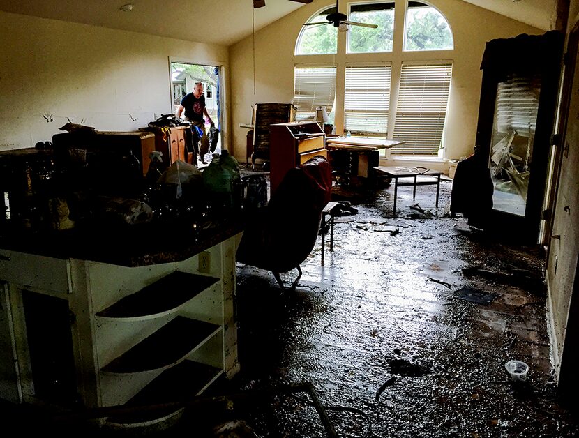  Larry Fick clears debris from his living room on Wednesday, May 27, 2015 after six feet of...