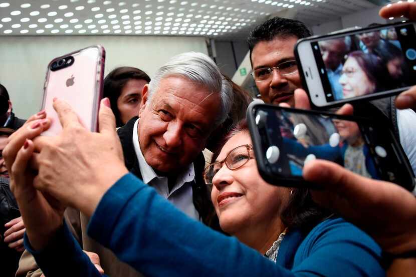 Mexican President Andres Manuel Lopez Obrador poses for a selfie with a passenger at Mexico...