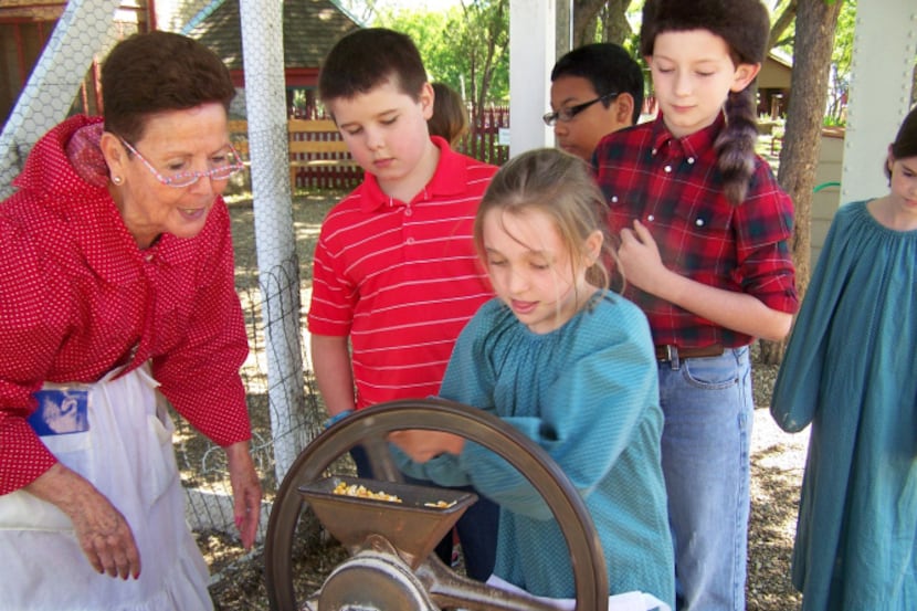 Children take turns grinding corn at Heritage Farmstead Museum.