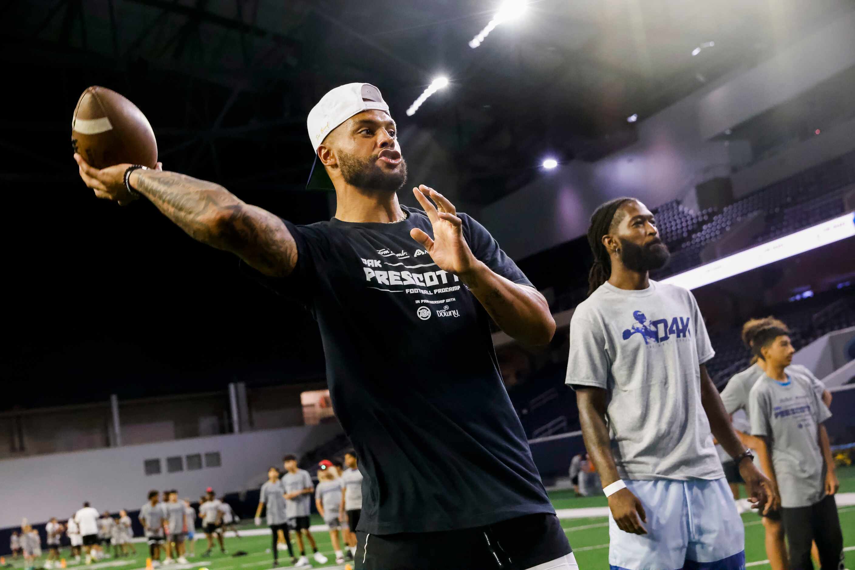 Cowboys quarterback Dak Prescott winds up his throw while running drills with students...