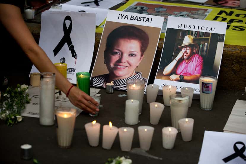 A candle is placed in front of pictures of murdered journalists Miroslava Breach (left) and...