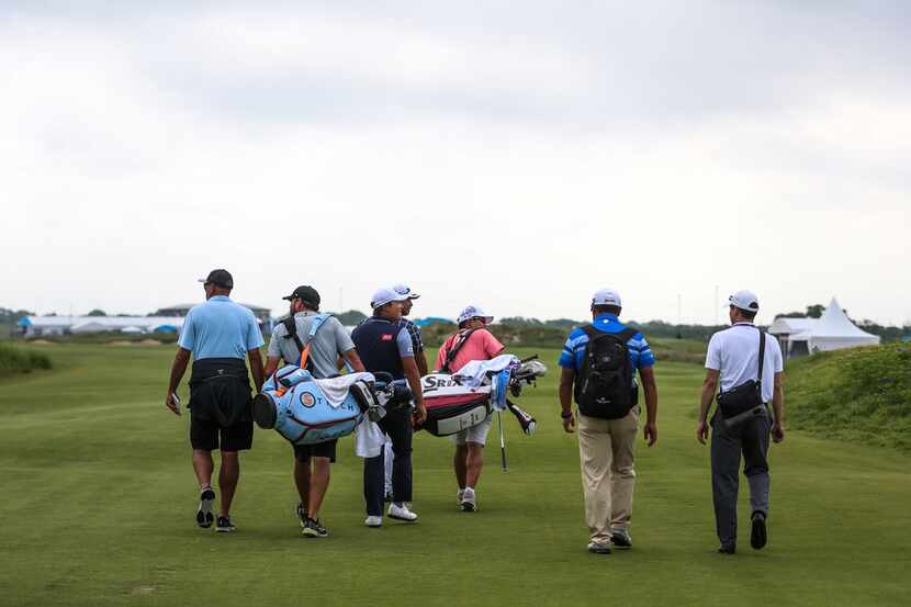 Players and their support teams step away from the first teeing box during practice on...