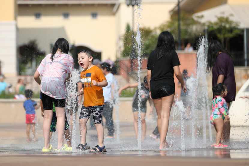 Matthew Ramirez cools off in a fountain at The Harbor Rockwall. Temperatures neared the...