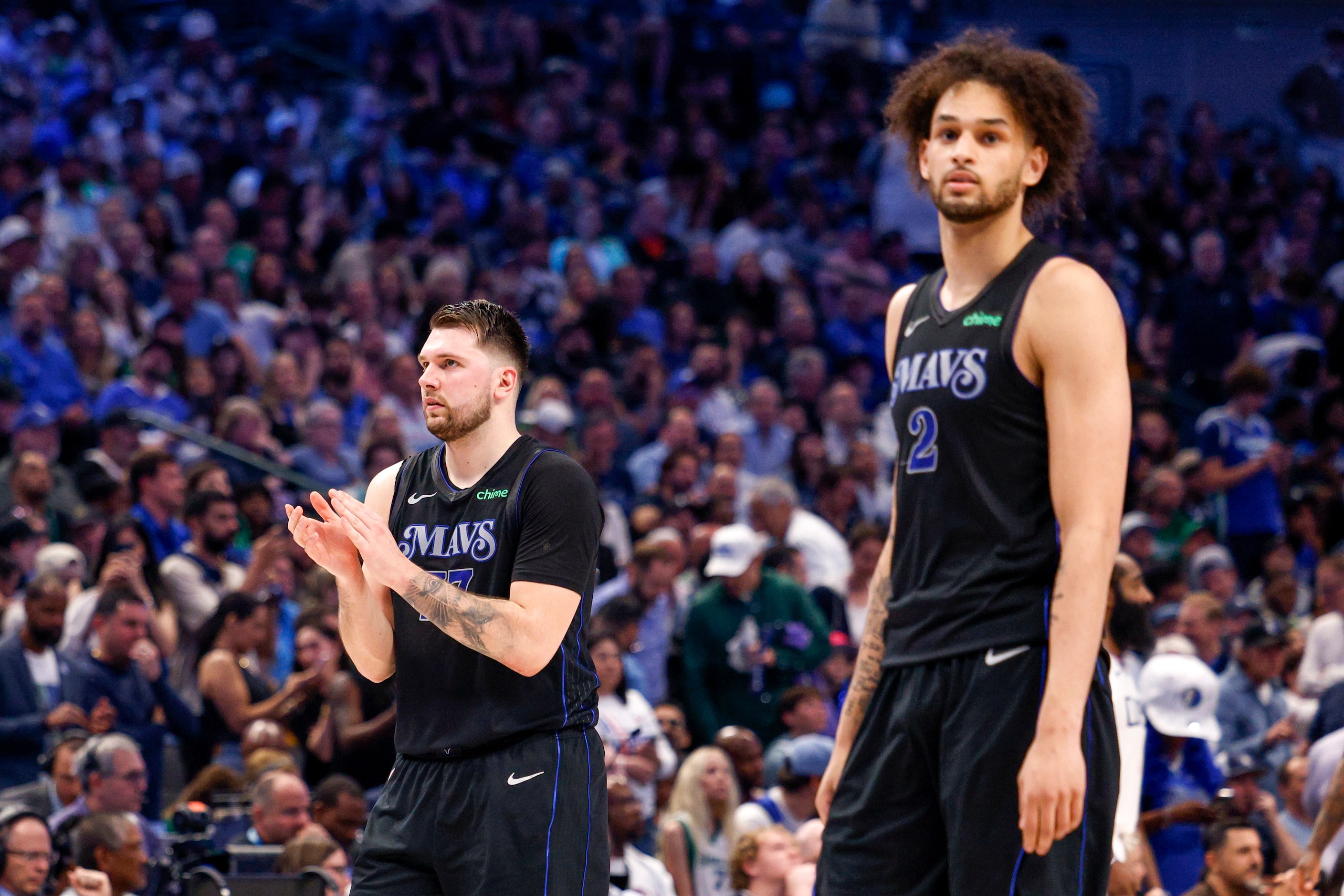 Dallas Mavericks guard Luka Doncic (77) claps as he walks to the bench alongside center...