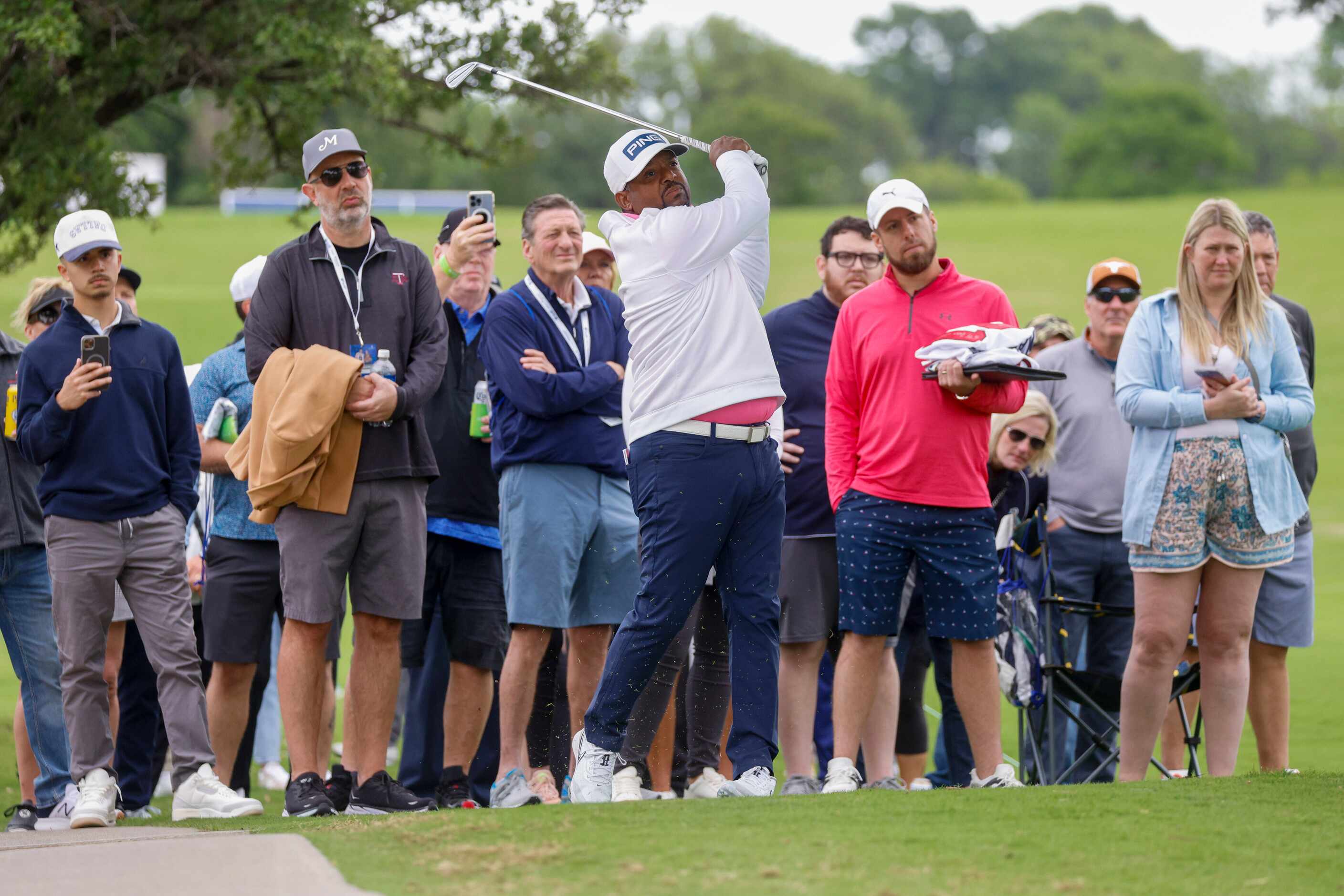 Fans watch as actor Alfonso Ribeiro plays a shot along the ninth fairway during the first...
