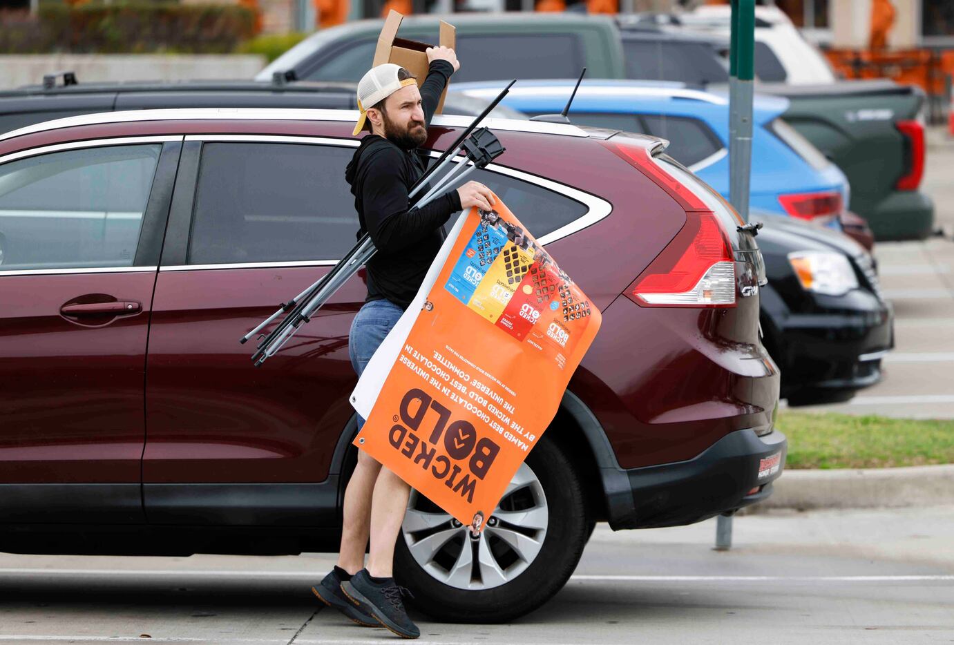 Deric Cahill exits his SUV carrying the Wicked Bold banner he sets up in the entrance of a...