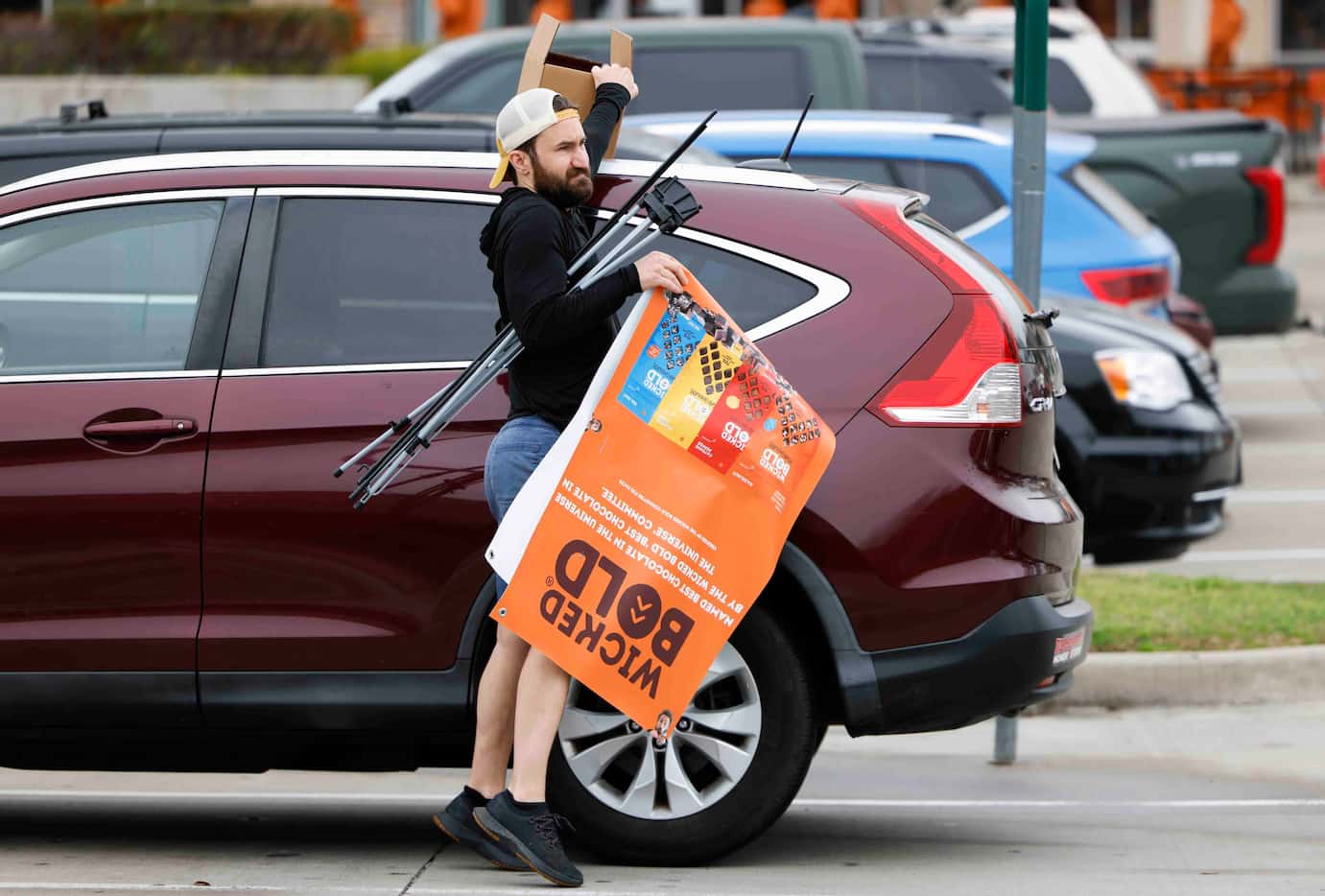Deric Cahill exits his SUV carrying the Wicked Bold banner he sets up in the entrance of a...