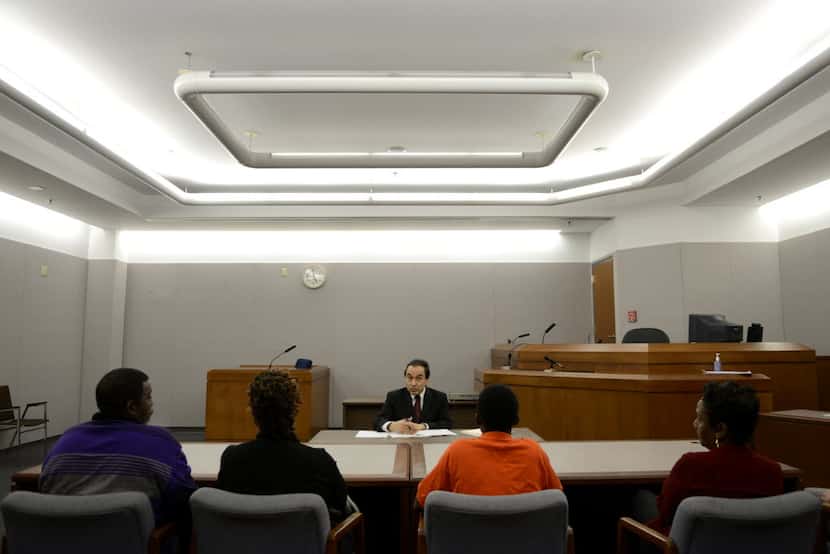 Judge Robert Herrera speaks to a boy, seated with his family and probation officer, who is...