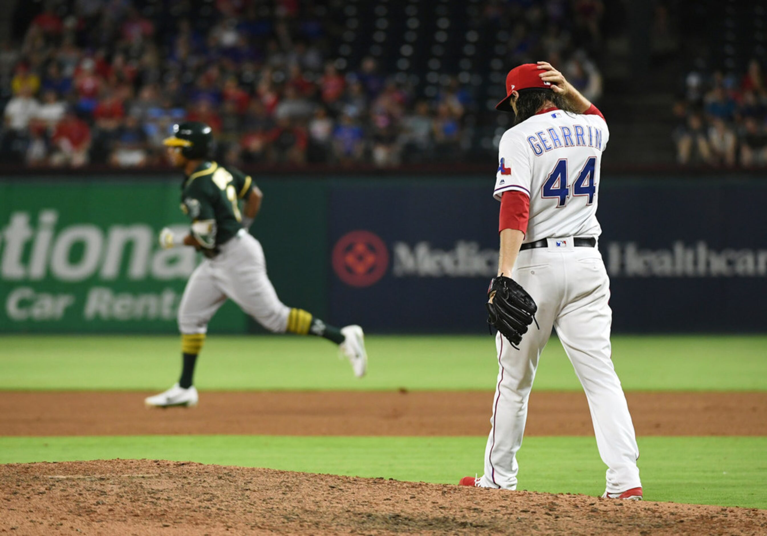 Texas Rangers relief pitcher Cory Gearrin walks back to the mound as Oakland Athletics'...