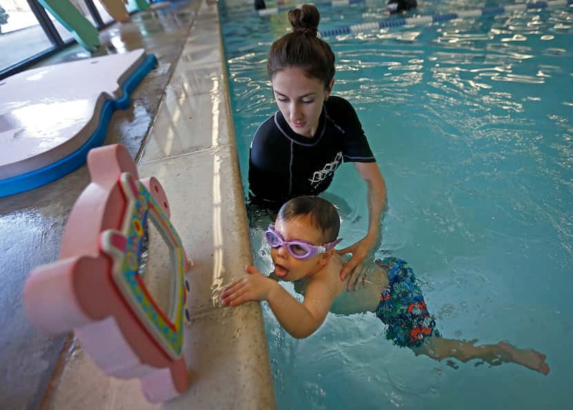 Instructor Ashlee Brannam teaches Truett Roush, 2, how to go back to the wall of the pool...