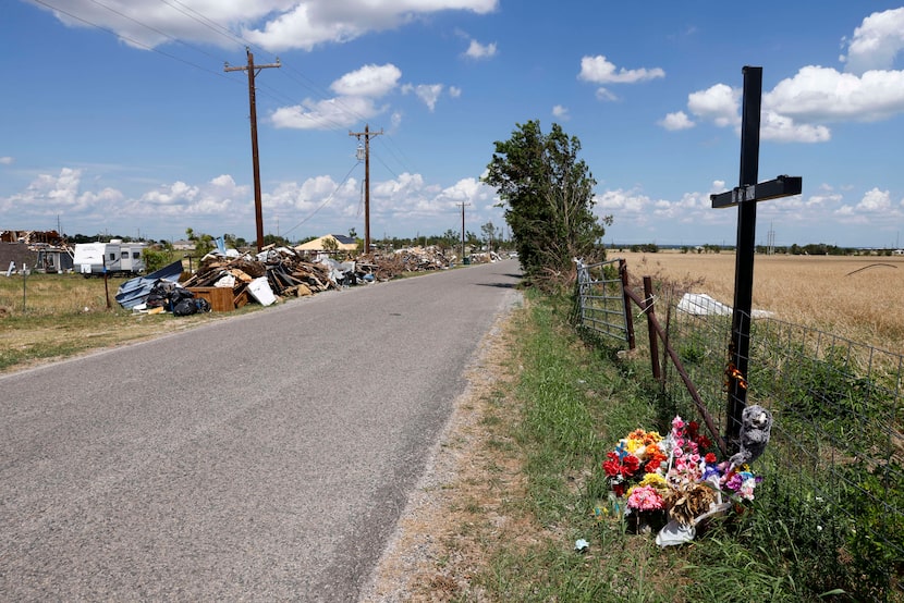 Debris from the May 25 EF3 tornado is seen along Lone Oak Road near a memorial for people...