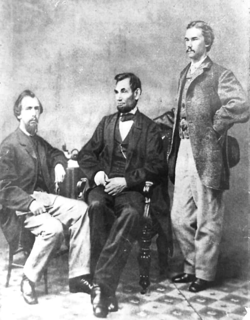 Photo shows President Abraham Lincoln seated between his private secretaries John G. Nicolay...