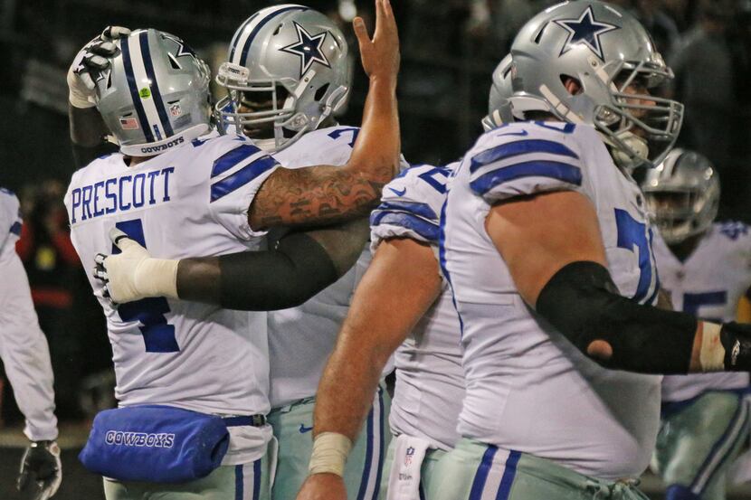 Dallas Cowboys quarterback Dak Prescott (4) gets a hug from offensive tackle Tyron Smith...