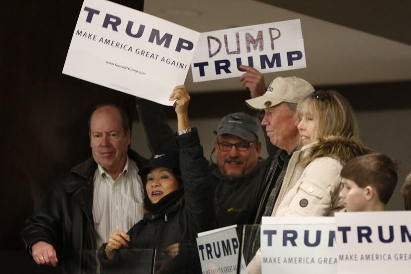 A Donald Trump supporter hold up her sign trying to block Walter Skold of Freeport, Maine,...