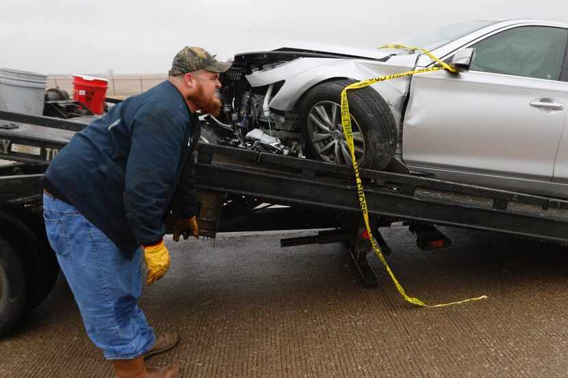 David Messer of J & S Towing hooks up a wrecked car on an ice-covered Highway 67/Hampton...