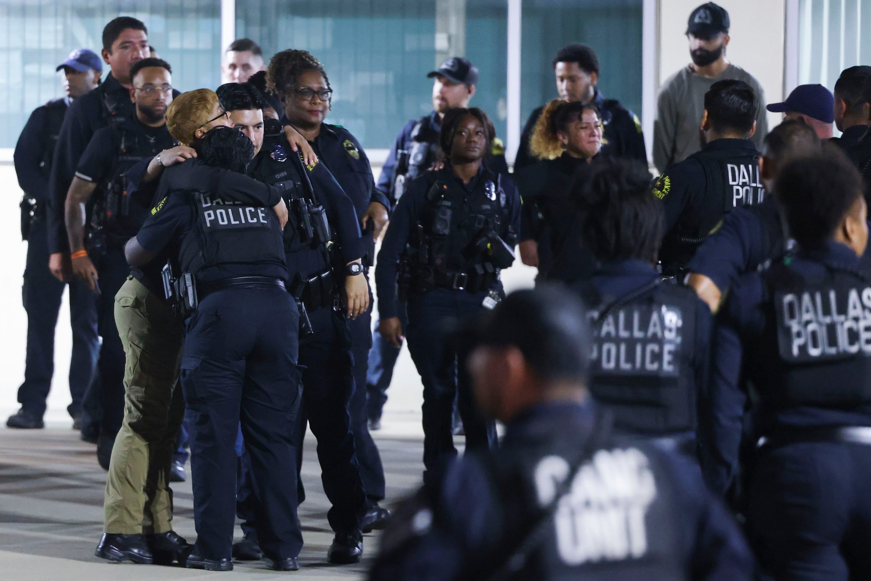 Dallas Police Department officers comfort each other following a guard of honor outside of...