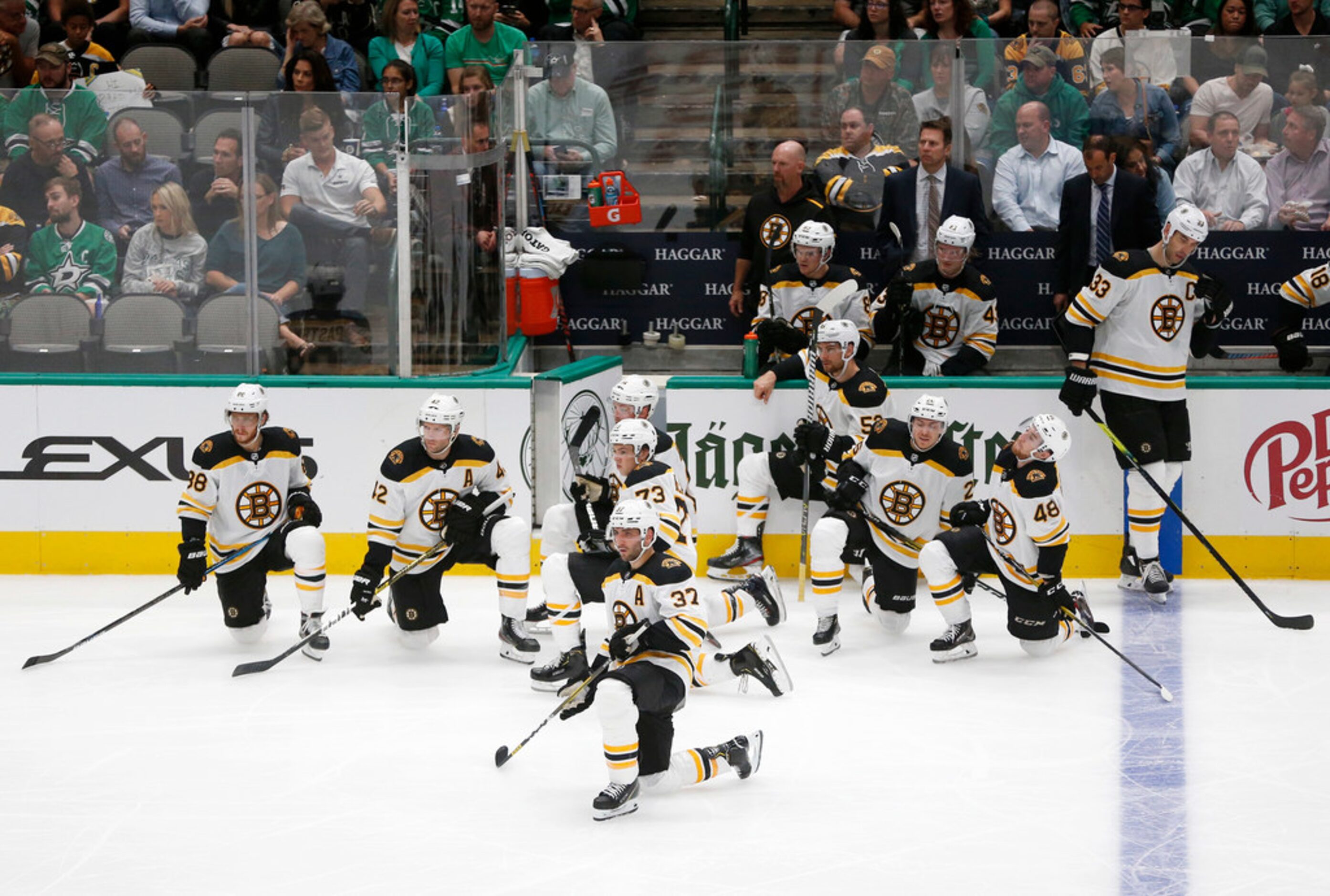 Boston Bruins players kneel as Dallas Stars defenseman Roman Polak (45) is tended to by the...