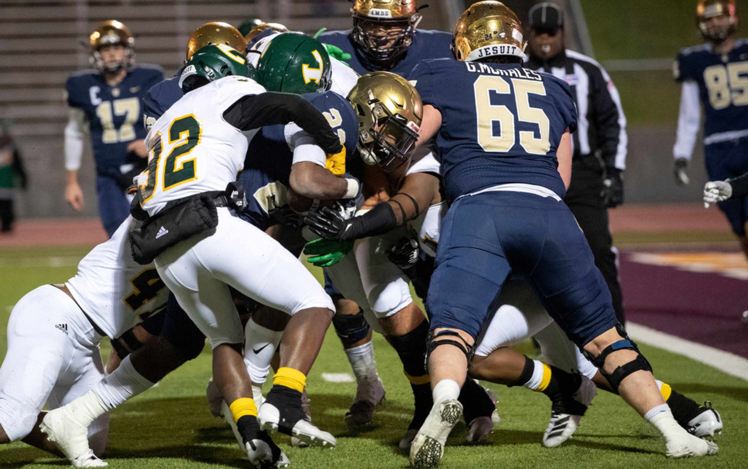 Jesuit senior running back E.J. Smith (22) drags a pile of Longview defenders into the end...