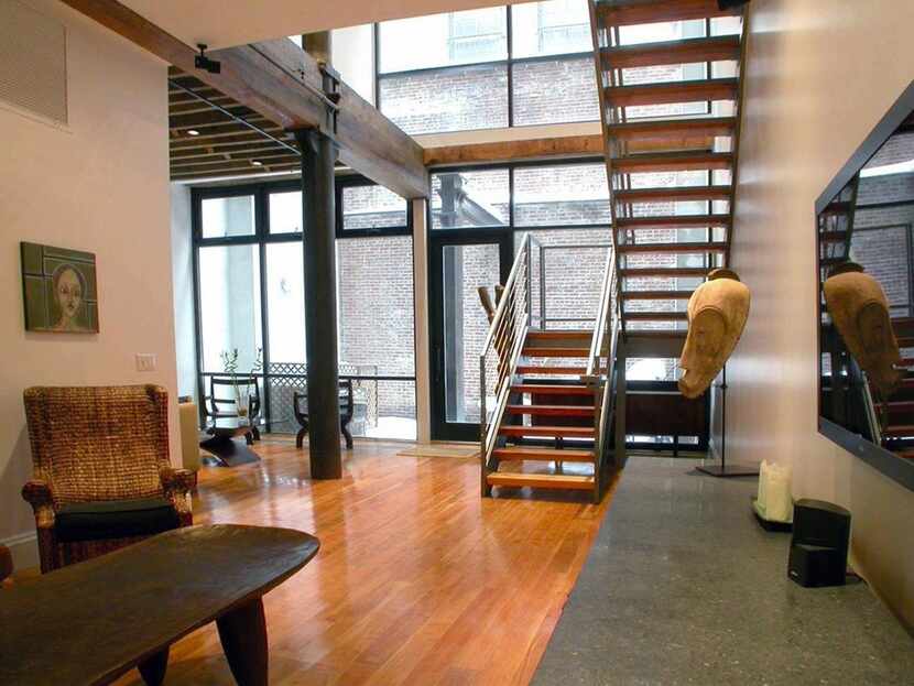 A loft staircase  uses salvaged and stained wood treads to connect the levels. A cable-style...