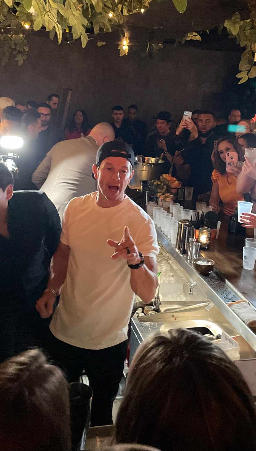 Mark Wahlberg pours tequila for fans behind the bar at La Neta in Dallas on March 2, 2023.