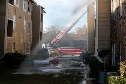 Firefighters put out hot spots during an apartment fire at the intersection of Interstate...