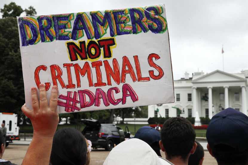 Una mujer sostiene un cartel frente de apoyo a DACA a la Casa Blanca. AP
