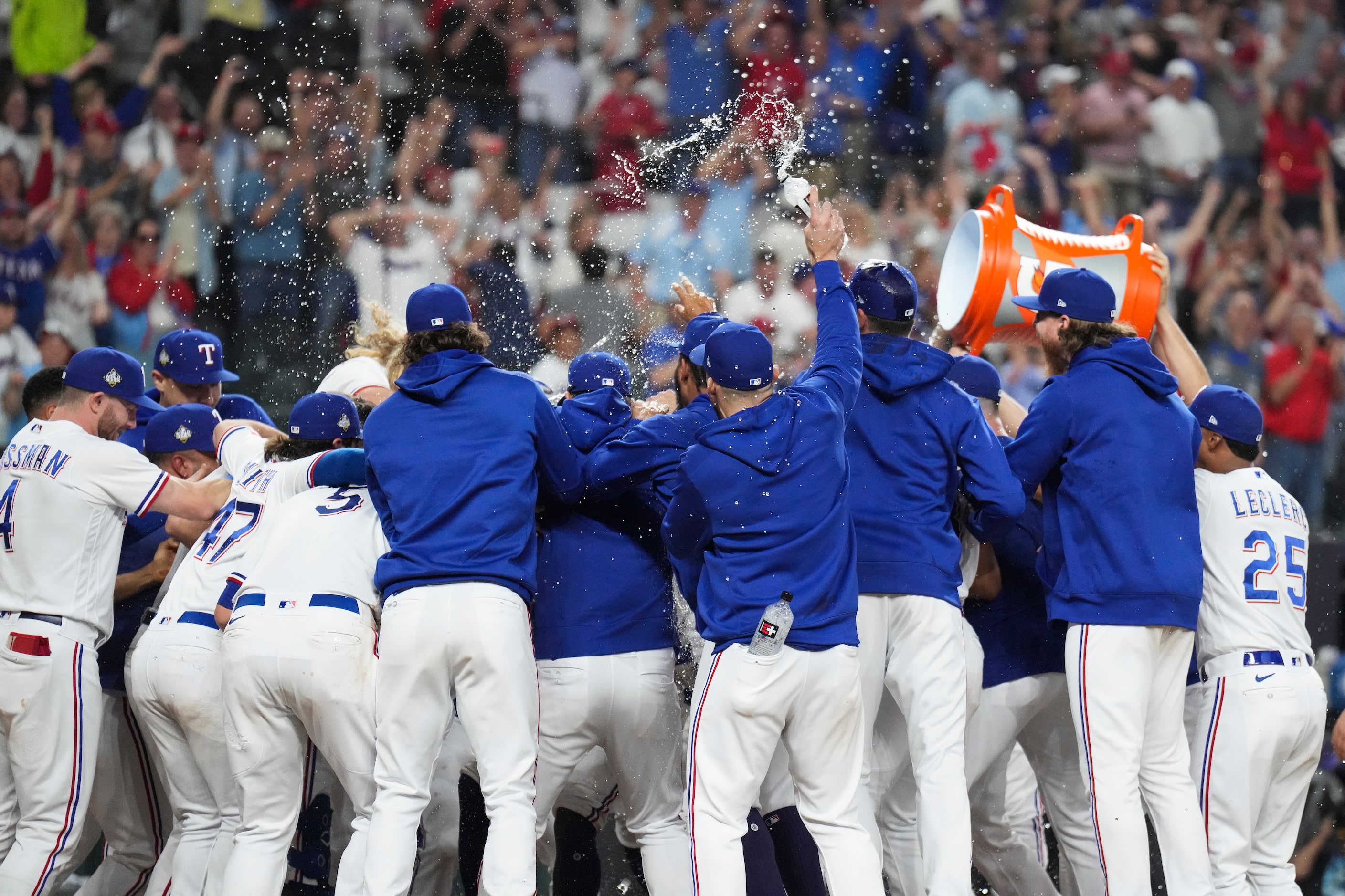 Texas Rangers' Adolis Garcia is mobbed at home plate after hitting a walk-off home run...